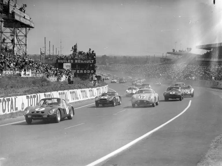 CIRCUIT DE LA SARTHE, FRANCE - JUNE 24: Mike Parkes / Lorenzo Bandini, SpA Ferrari SEFAC, Ferrari 330 LM/GTO, leads at the start from Jean Kerguen / Jacques Dewes, Aston Martin DB4 GT (#12), Olivier Gendebien / Phil Hill, SpA Ferrari SEFAC, Ferrari 330 TRI/LM (#6), and Maurice Charles / John Coundley, Maurice Charles, Jaguar E-type (#8) during the 24 Hours of Le Mans at Circuit de la Sarthe on June 24, 1962 in Circuit de la Sarthe, France. (Photo by LAT Images)