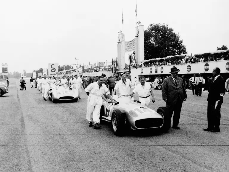 Großer Preis von Italien in Monza, 11.09.1955. Mechaniker schieben die vier Mercedes-Benz Formel-1-Rennwagen W 196 R und W 196 Stromlinie an den Start, Rennleiter Neubauer am vorderen Wagen.