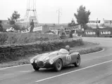 Having rounded a corner, this Works-entered OSCA MT4 hurtles past advertisement banners at 1954 24 Hours of Le Mans on 13th June. Lance Macklin and Pierre Leygonie would go on to complete 254 laps before being disqualified for receiving outside help.