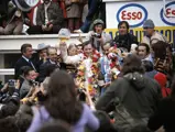Winner of the 1972 24 Hours of Le Mans, Graham Hill, triumphantly raises his glass trophy filled with champagne to celebrate his victory.