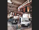 A colour photo shows chassis 4500012 on the 1954 Earls Court Motor Show stand alongside a Mercedes-Benz 220.