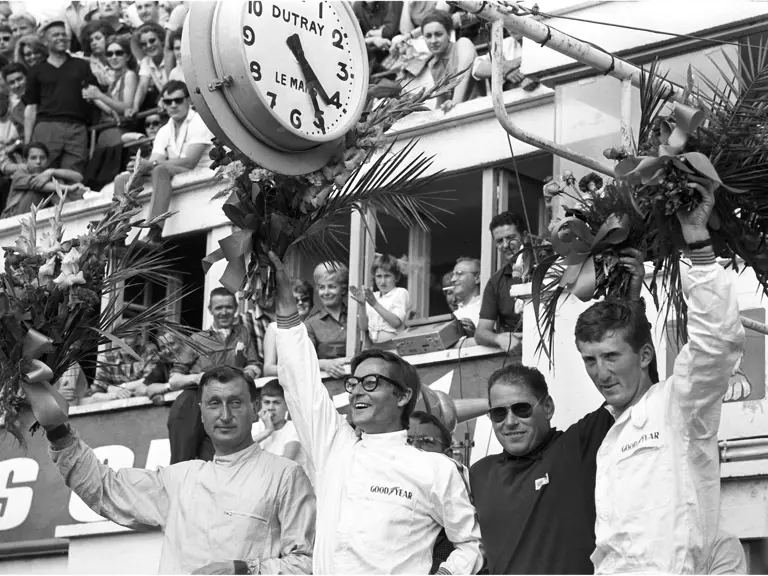 Team driver’s Masten Gregory (second from left) and Jochen Rindt (first on right) celebrate their impressive 1965 24 Hours of Le Mans victory at the challenging Circuit de la Sarthe. Photo by Rainer Schlegelmilch.