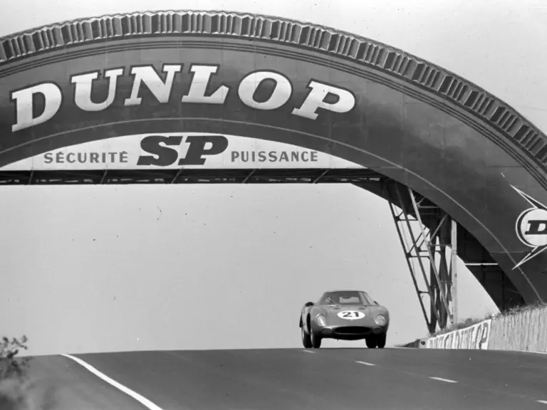 Chassis no. 5893, NART entry #21, races under the iconic Dunlop Bridge at the 1965 24 Hours of Le Mans.