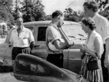 Jack Broadhead, Stirling Moss, and Bob Berry with Mrs. Berry discuss OKV 2 in the foreground.